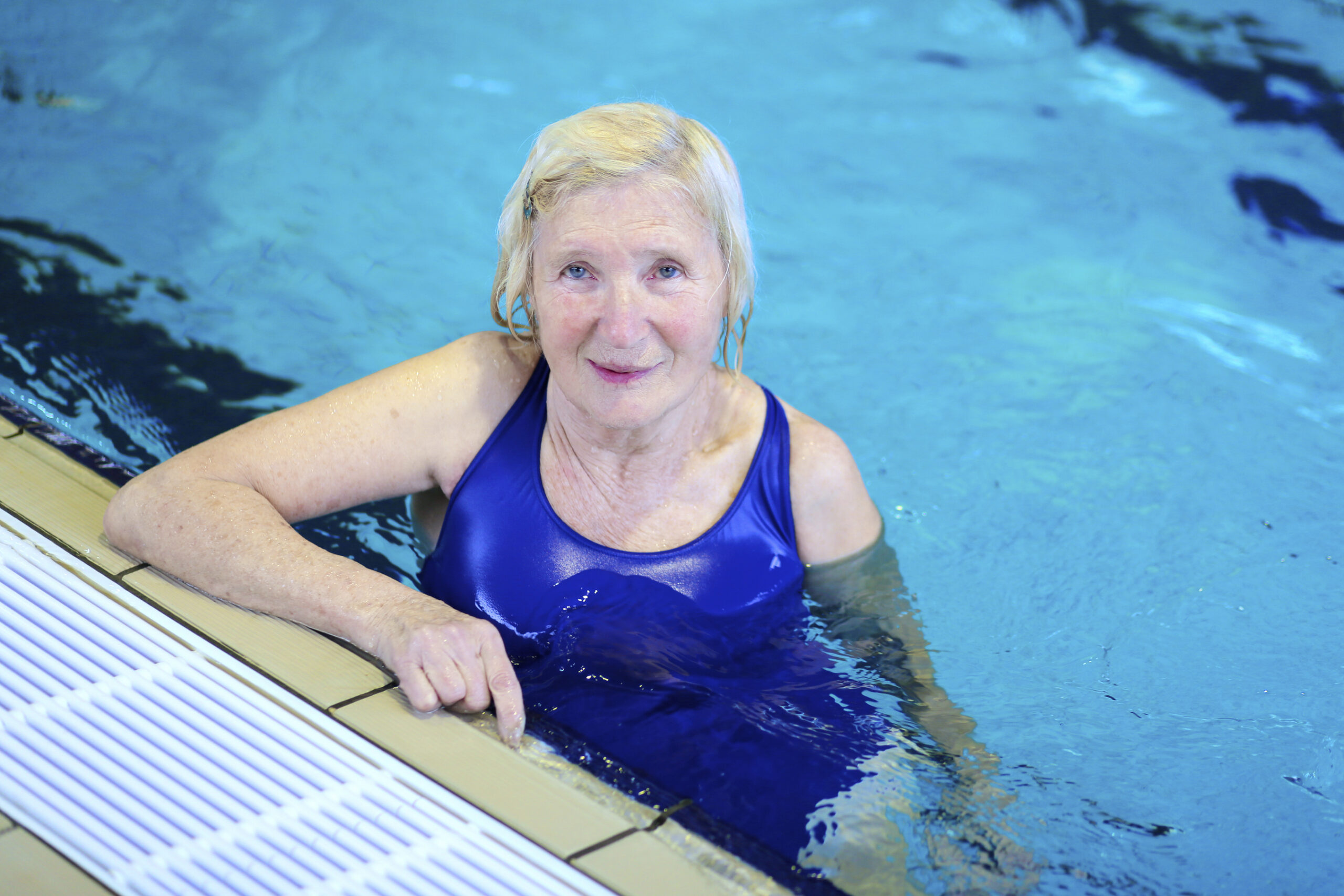 Happy healthy senior woman enjoying sportive lifestyle swimming in the pool - active retirement concept